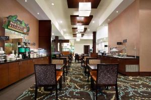 费耶特维尔Embassy Suites by Hilton Fayetteville Fort Bragg的一间带桌椅的餐厅和一间酒吧