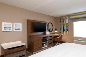 迈尔斯堡迈尔斯堡汉普顿酒店及套房 - 殖民地大道的一间卧室配有一张桌子、一台电视和一张床