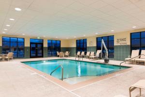 曼彻斯特哈特福德曼彻斯特汉普顿酒店的酒店大堂的游泳池,配有桌椅