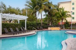 霍姆斯泰德Hampton Inn & Suites Homestead Miami South的一个带椅子、天篷和棕榈树的大型游泳池