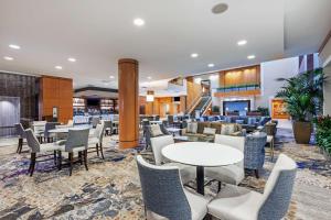 休斯顿Embassy Suites by Hilton Houston-Energy Corridor的一个带桌椅的大堂和一间餐厅