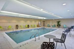 昆斯伯里Home2 Suites by Hilton Queensbury Lake George的游泳池位于酒店客房内,配有椅子和桌子