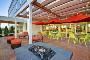 昆斯伯里Home2 Suites by Hilton Queensbury Lake George的一个带桌椅和红色遮阳伞的庭院