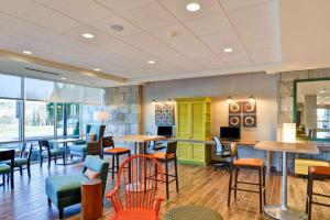 温斯顿·塞勒姆Home2 Suites By Hilton Winston-Salem Hanes Mall的餐厅设有多彩的桌椅和窗户。