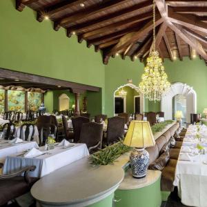 危地马拉Hilton Guatemala City, Guatemala的一间带桌椅和吊灯的餐厅