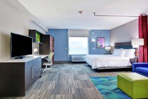 斯普林代尔Home2 Suites By Hilton Springdale的配有一张床和一台平面电视的酒店客房
