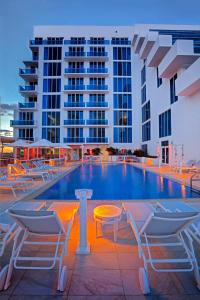 劳德代尔堡Hotel Maren Fort Lauderdale Beach, Curio Collection By Hilton的酒店游泳池设有椅子,酒店大楼