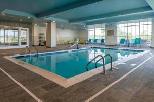 Sunnybrook AcresHilton Garden Inn By Hilton Fort Wayne North的酒店大堂的游泳池,设有蓝色椅子