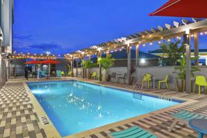 杰克逊维尔Home2 Suites By Hilton Jacksonville South St Johns Town Ctr的夜间游泳池,配有桌椅