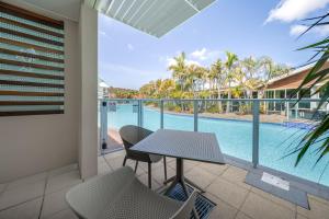 萨拉曼德湾Oaks Port Stephens Pacific Blue Resort的一个带桌椅的庭院和一个游泳池