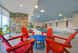 哥伦布Home2 Suites By Hilton Columbus的一个带红色椅子和蓝色桌子的游泳池