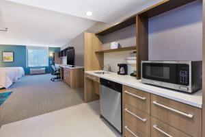 威尔明顿Home2 Suites Wilmington的酒店客房设有厨房和卧室