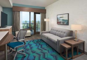 帕诺滩Home2 Suites By Hilton Pompano Beach Pier, Fl的酒店客房配有沙发、书桌和椅子