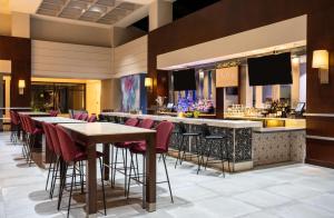 费尔法克斯Hilton Fairfax, Va的一间带桌子的餐厅以及一个带红色椅子的酒吧