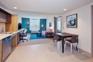 Byron CenterHome2 Suites By Hilton Grand Rapids South的厨房以及带桌椅的起居室。