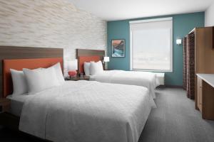 霍布斯Home2 Suites By Hilton Hobbs的酒店客房设有两张床和窗户。