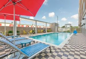 El CampoHome2 Suites By Hilton El Campo的一个带椅子和红伞的游泳池