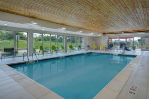 肯特伍德Home2 Suites By Hilton Grand Rapids Airport的大楼内带桌椅的大型游泳池