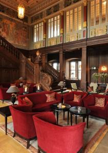 艾珍明希豪森城堡酒店的大楼内带红色桌椅的大堂