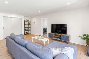 马斯特顿High Street Pool House的客厅配有蓝色的沙发和电视