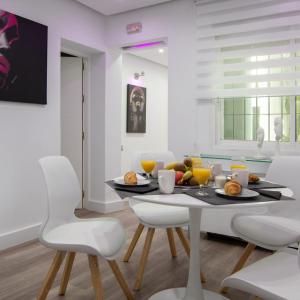 马拉加Malaga Chic jacuzzi y playa的一间带桌子和白色椅子的用餐室