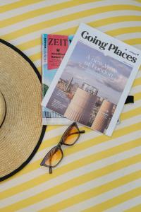 卡塔海滩Nonnee Hotel Kata Beach Phuket的坐在杂志旁的一顶帽子和一副眼镜