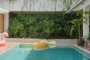 卡塔海滩Nonnee Hotel Kata Beach Phuket的植物前带泳池面的游泳池
