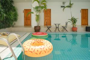 卡塔海滩Nonnee Hotel Kata Beach Phuket的游泳池设有两把椅子,里面装有甜甜圈