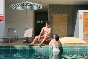 卡塔海滩Nonnee Hotel Kata Beach Phuket的坐在游泳池边的男人和女人
