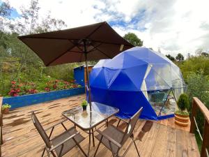 瓜塔维塔Glamping blue.的甲板上配有桌椅和遮阳伞