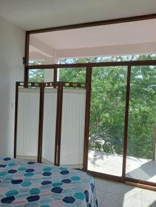 La SabrosaCasa Laud Chacahua的一间卧室设有一张床和一个大型玻璃窗