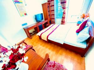 Xuân ÐàiLam Hong Hotel的一间卧室配有一张床和一张鲜花桌子