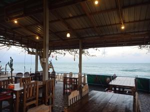 Ban Thung OHOME NO 3 khanom的海滩上的餐厅,配有桌椅