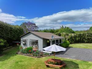 凯里凯里Kendall Cottage - Kerikeri New Zealand的一个带雨伞和野餐桌的小房子