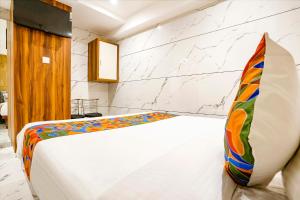 孟买FabHotel Shubham Inn的卧室配有白色床和色彩缤纷的枕头