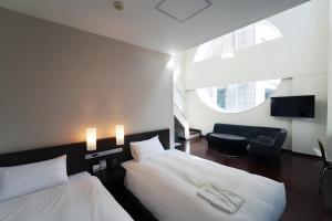 仙台KOKO HOTEL Sendai Kotodai Park的酒店客房,配有两张床和椅子