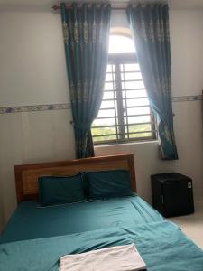 槟知Khách Sạn Vinhomes Huỳnh Hotel的一间卧室配有床和蓝色窗帘的窗户
