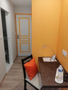 RavelAU CLOS DE L'ETANG的配有桌子和椅子及橙色枕头的房间