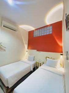 棉兰JIYO BOUTIQUE HOTEL by SAJIWA的红色墙壁的客房内的两张床