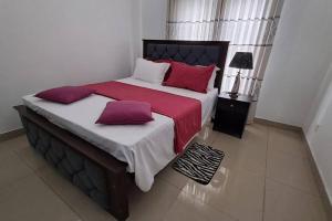 贾埃勒Spacious Greenery Homely Home的一间卧室配有一张带红色和白色枕头的大床