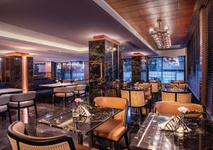 曼谷SAMALA Hotel Bangkok的一间在房间内配有桌椅的餐厅