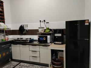 关丹Firdzura Home Semi D的厨房配有黑色冰箱和微波炉。
