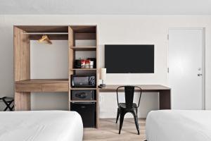 基西米Developer Inn Highway, A Howard Johnson by Wyndham的一间卧室配有书桌、电视和椅子