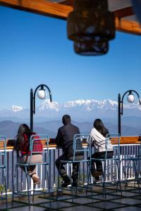 阿尔莫拉Kasar Himalaya Holiday Home, Binsar Rd的一群坐在桌子上的人,看着群山