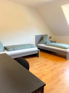 新乌尔姆Apartment über Neu Ulm's Dächern, 2 Schlafzimmer inkl. Stellplatz的配有两张床铺、木地板和桌子的客房