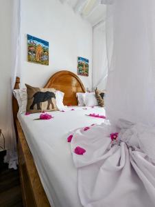 吉汶瓦巴哈蒂酒店的一张白色的大床,上面有粉红色的花朵