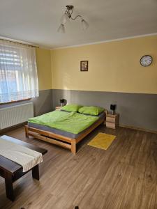 BiałaGościniec w Starym Młynie的一间卧室配有一张带绿色床单的床和时钟