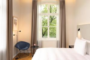 萨尔布吕肯ESPLANADE Saarbrücken的一间卧室设有一张床、一个窗口和一把椅子