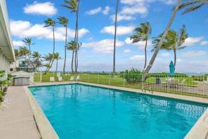 拉耶Beautiful Beachfront Condo的一个种有棕榈树的大型蓝色游泳池