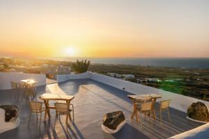 伊亚Sun Angelos Oia - Luxury Cave Suites的一个带桌椅的屋顶露台,享有日落美景
